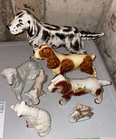 Overall view of seven ceramic dog figurines of varying sizes and colors arranged on a surface