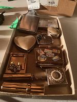 Collection of cosmetic cases including heart-shaped compact, travel sticker decorated case, pearl decorated compact, and four lipstick holders.