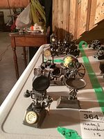 Photo showing metal miniatures arranged on table with rotary phones, horse-drawn wagon, globe, motorcar clock, and oil lamp visible.