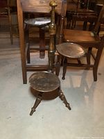 Full view of the wood 3 tier plant stand in basement showing overall structure with three circular shelves and three tripod legs.