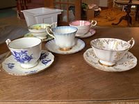 Photo showing all five teacups and saucers on a wooden surface, displaying distinct floral and color patterns.