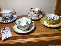 Four teacups and matching saucers displayed together showing different patterns and makers.