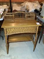 Front angled view of wicker and wood desk with upper storage compartments and lower shelf in a basement setting
