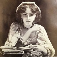 Close-up of albumen print portrait of young woman seated at desk, showing fine details of dress, jewelry, and facial features