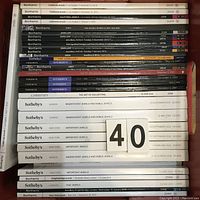 Stack of auction catalogs from Bonhams, Sotheby's, and Christie's, showing titles mostly about fine jewelry and Americana art sales, varying colors and sizes.