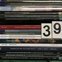 Stacked spines of multiple art auction catalogs showing titles and auction locations/dates