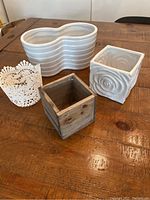 All four planters displayed together on a wooden table showing size comparison and materials.