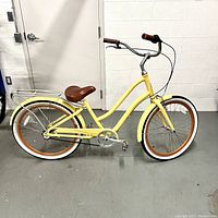 Full side view of the entire cruiser bicycle showing frame style, color, wheels, handlebars and saddle