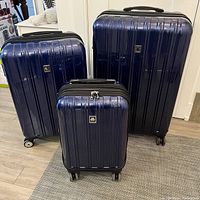 Front view of all three nested suitcases: extra small carry-on in front, medium and large behind