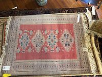 View of the full area rug showing its rectangular shape, central geometric medallion pattern, fringed edges, and border design on wood flooring.