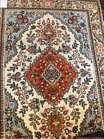 Close-up of central geometric floral pattern in red, cream, light blue, and tan colors