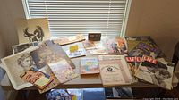Overview of all items on table including magazines, comic book, postcards, guides, and posters.