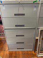 Full front view of the vertical 5-drawer metal filing cabinet with horizontal metal handles and lock.