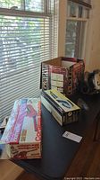 Photo of all three boxed items on a table near window: Redeye circular saw, SteamX steam brush, and Homelite cordless shrub trimmer.