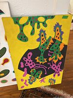 Abstract painting with yellow background and organic shapes in green, purple, orange, pink and black.