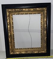 Full view of the antique wooden picture frame with gold and black detailing.