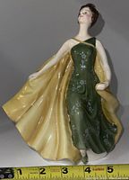 Front view of Royal Doulton Alexandra HN2398 porcelain figurine showing green dress with floral details and flowing yellow cape.