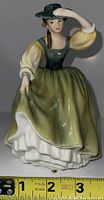 Front view of Royal Doulton Buttercup porcelain figurine showing woman in green dress and hat.