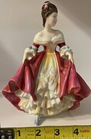 Front view of Royal Doulton Southern Belle porcelain figurine with tape measure for approximate height.