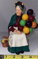 Front view of Royal Doulton Balloon Seller figurine showing the woman's face, colorful balloons, and basket with flowers.