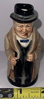 Front view of Royal Doulton Toby Mug figurine showing seated man character with black hat and blue bow tie.