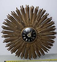 Full view of the vintage Burwood starburst wall clock showing the large wooden rays and central black clock face with Roman numerals.