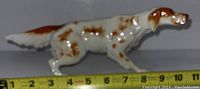 Side view of vintage porcelain dog figurine with measuring tape showing length approximately 7 inches.