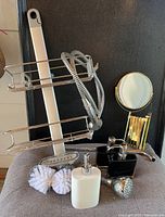 Front view of full lot showing shower caddy, both shower heads, extendable arm mirror, soap dispensers and white sponge items.