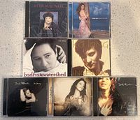 Photo showing 7 CD albums by Canadian female singers: Rita MacNeil, Celine Dion, k.d. lang (two albums), Sarah McLachlan (three albums), all in jewel cases, arranged on a flat surface.