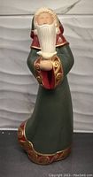 Front view of a ceramic Santa Claus figurine holding a white dove, showing detailed robe with red and gold trim.