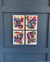 Four 8x10 neon abstract canvases arranged in a grid against a wall showing vibrant, colorful, highly textured paint strokes.