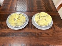 Two round ceiling light fixtures showing the internal side with yellow insulation and wiring on a wooden surface.