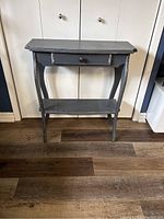 Front view of the antique gray wooden console table showing the full structure including legs, drawer, and lower shelf.