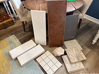 Overview photo showing assortment of flooring materials including laminate planks and various tiles placed on wooden floor near furniture.