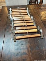 Set of 12 wooden hangers arranged on a wooden table, showing metal clips and wooden body