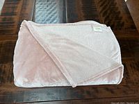 Folded pink plush blanket showing soft smooth texture and stitching