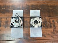 Two rectangular sconces face up showing metal mounting plates and wiring arranged on frosted glass panels.