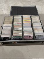 Open flight case displaying five compartments filled with numerous CDs stacked vertically.