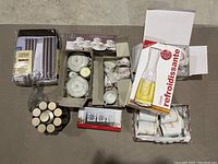 Overview of boxed porcelain tea sets, new curtains in plastic packaging, glass decanter, candles, and additional tea cups in open boxes