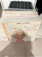 Side view of a stack of vinyl records showing the album cover of Doris Day's "I Have Dreamed" on top, within plastic protective sleeves.
