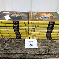 Photo showing all 14 Nancy Drew hardcover books stacked horizontally with spines visible, highlighting the vintage yellow spine design and some front cover art.