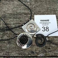 Three metal pendant necklaces laid on wooden surface, showing full pendants and cords