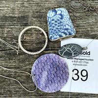 Photo showing all four pendants: purple textured shell, blue and white ceramic rectangle, circular rhinestone, vintage grey oval earring piece pendant.