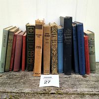 Frontal view of all 15 books lined up vertically showing various classic titles and aging on spines