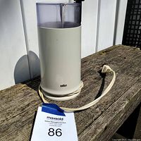 Full view of vintage Braun coffee grinder with clear lid and power cord coiled at base.