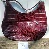 Front view of dark red crocodile textured Danier leather purse with visible front zipper pocket and single shoulder strap.