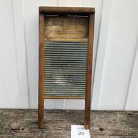 Full front view of the small Baby Globe washboard showing wooden frame and metal ridged wash surface with visible wear.