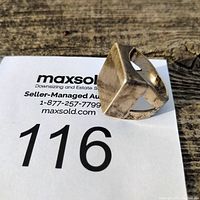 Front and angled view of a sterling silver ring with a square face showing tarnish and wear.