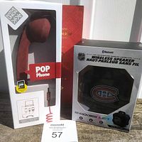 Photo showing the boxed Pop Phone handset with red color and spiral cord, and the Montreal Canadiens wireless speaker box with NHL logo and Shockbox LED branding.
