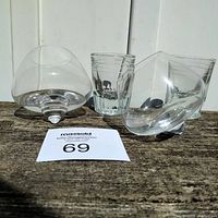 Photo of 2 wobbly scotch glasses with pointed bases along with 2 vintage LLBO shot glasses on wooden surface